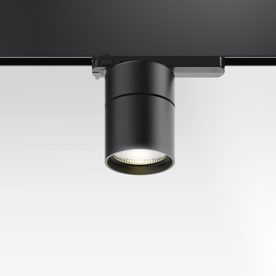 Artemide Hoy Spot 3-Phase Track: black cylindrical LED spotlight mounted on black track rail, emitting warm white downward light - 2