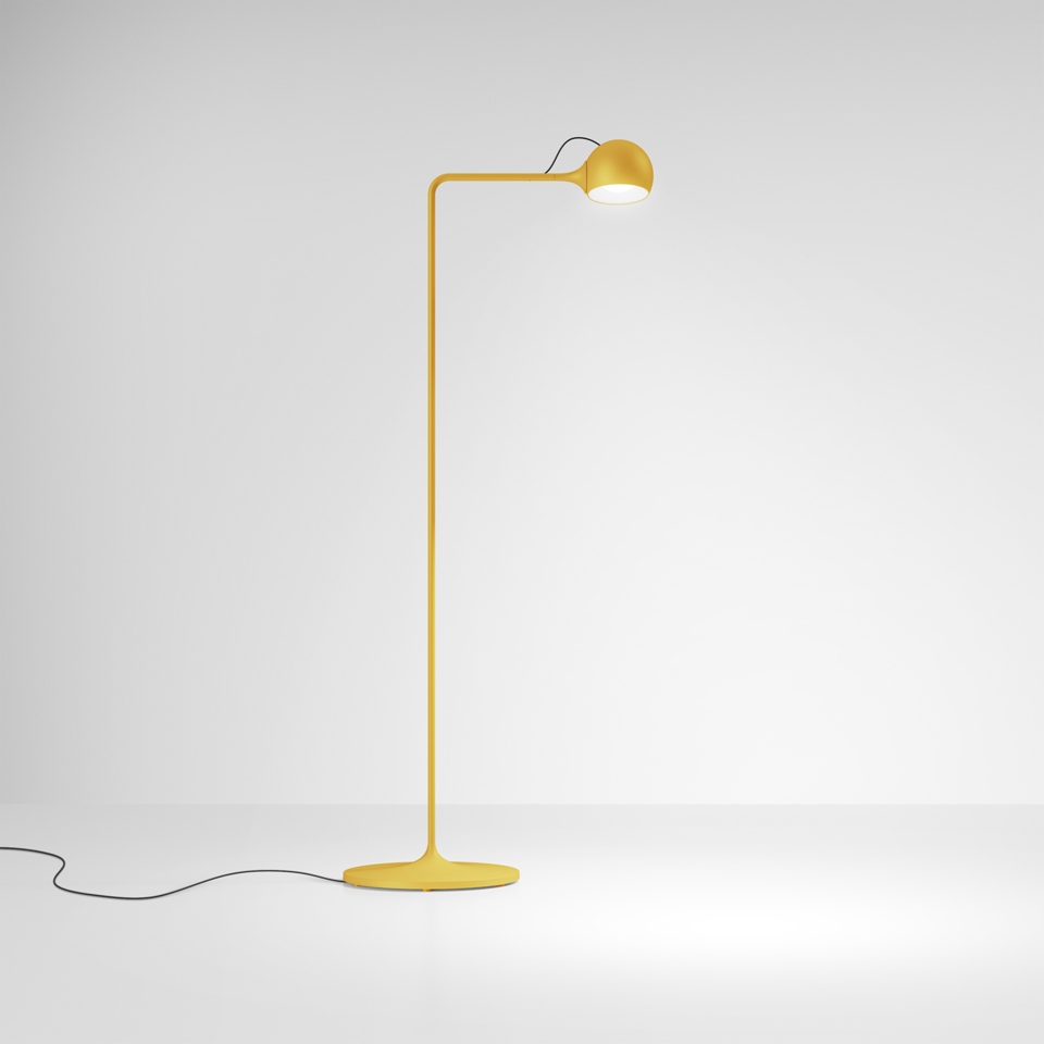 Artemide Ixa floor lamp in yellow, featuring a slender curved stem, round adjustable head, and flat circular base with black cord
