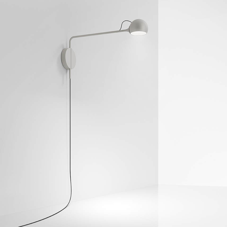 Artemide Ixa wall lamp in white, featuring a long horizontal arm, spherical adjustable head, and black cord on white wall