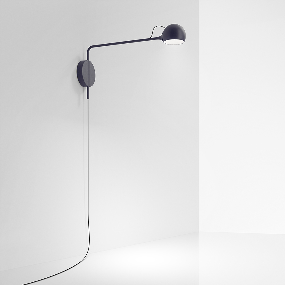 Artemide Ixa wall lamp in dark blue, featuring a long adjustable arm with spherical head and visible cord along the wall