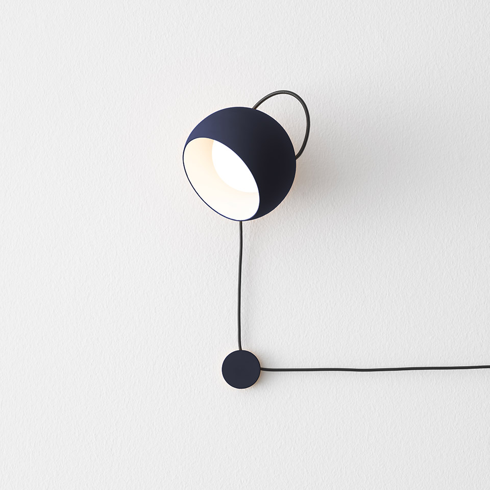 Artemide Ixa wall lamp in dark blue, featuring a dome-shaped shade, curved handle, black cord, and circular dimmer switch