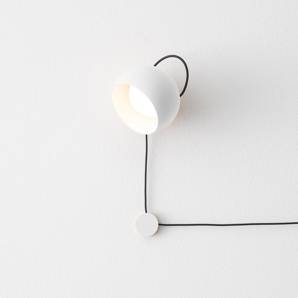 Artemide Ixa wall lamp: white dome-shaped head on black curved arm, adjustable orientation, with black cord and round base