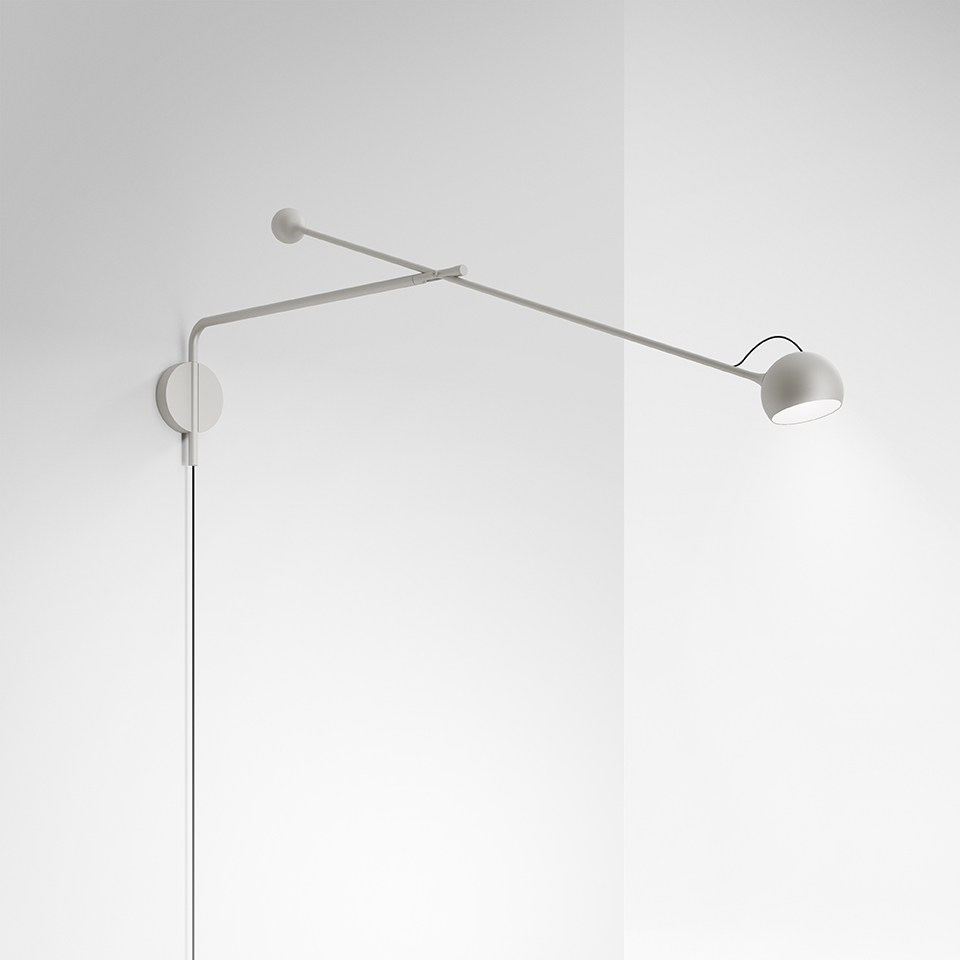 Artemide Ixa wall lamp in white, featuring a long adjustable arm with a small spherical rotating head, mounted on a corner wall