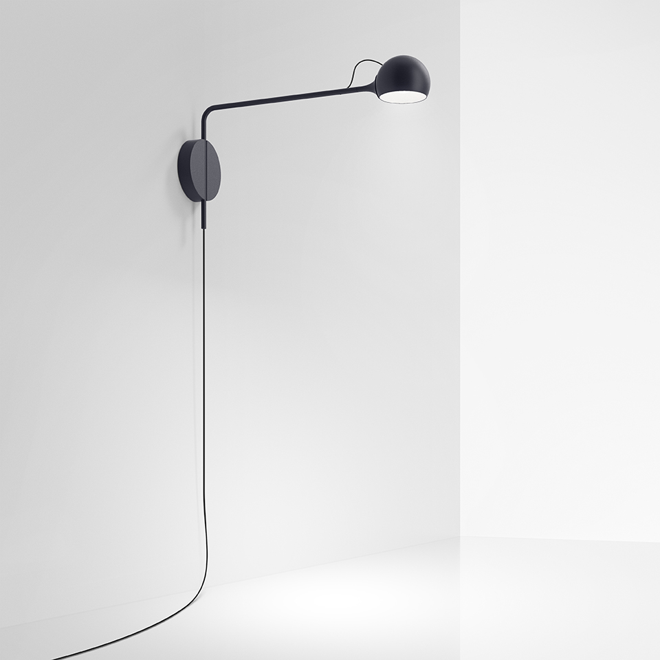 Artemide Ixa wall lamp in black, featuring a slim adjustable arm, spherical LED head, and circular wall mount with visible cord