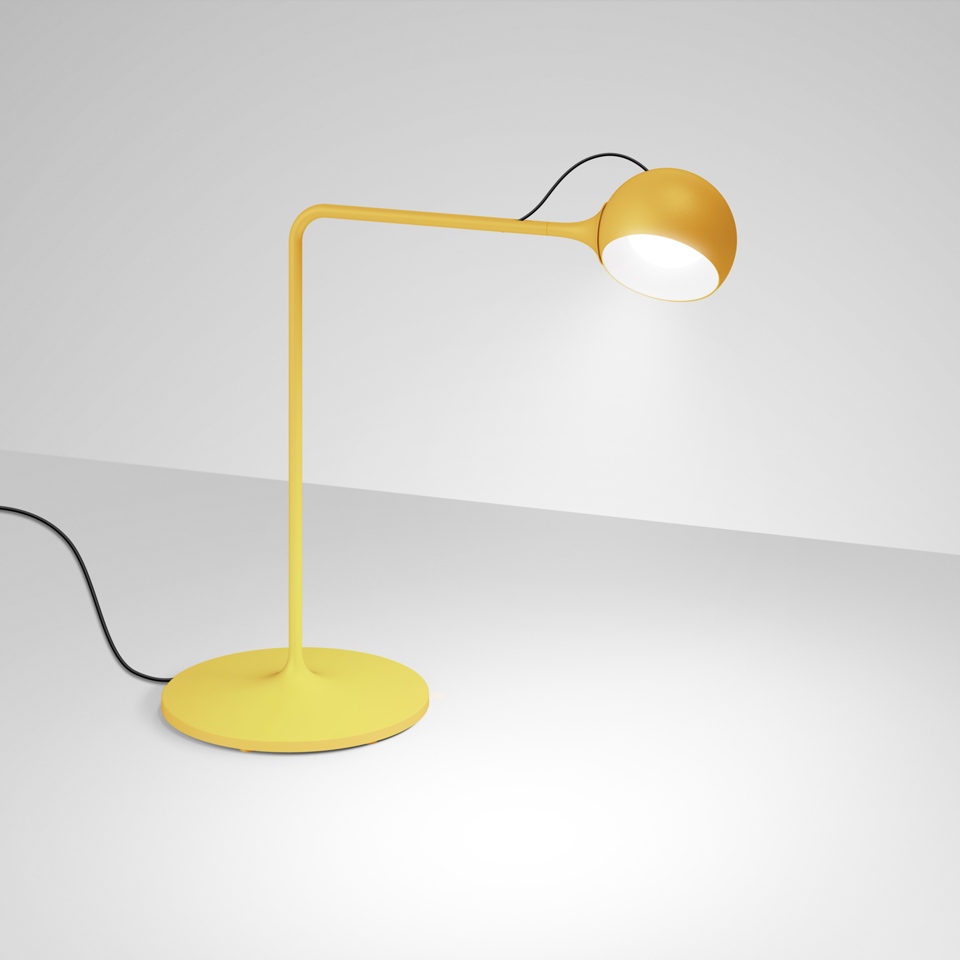 Artemide Ixa table lamp in yellow with round base, angled arm, and spherical adjustable head emitting warm white light