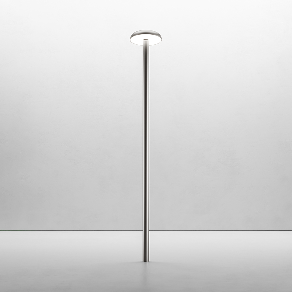 Artemide Knop floor lamp: slim polished metal pole with a flat circular LED diffuser on top, providing upward and downward light