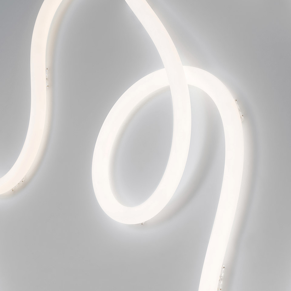 Artemide La Linea 25: glowing flexible LED tube forming elegant curves and loops against a light grey background