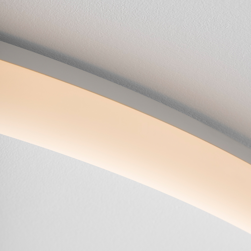 Close-up of Artemide La Linea curved LED strip light mounted near ceiling, emitting warm white diffused light