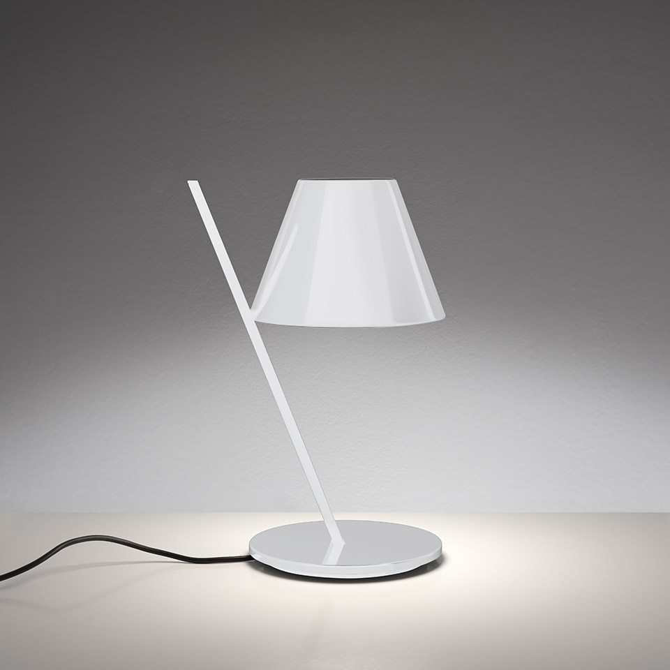 Artemide La Petite table lamp in white, featuring a diagonal stem, conical shade, and circular base with soft downward light
