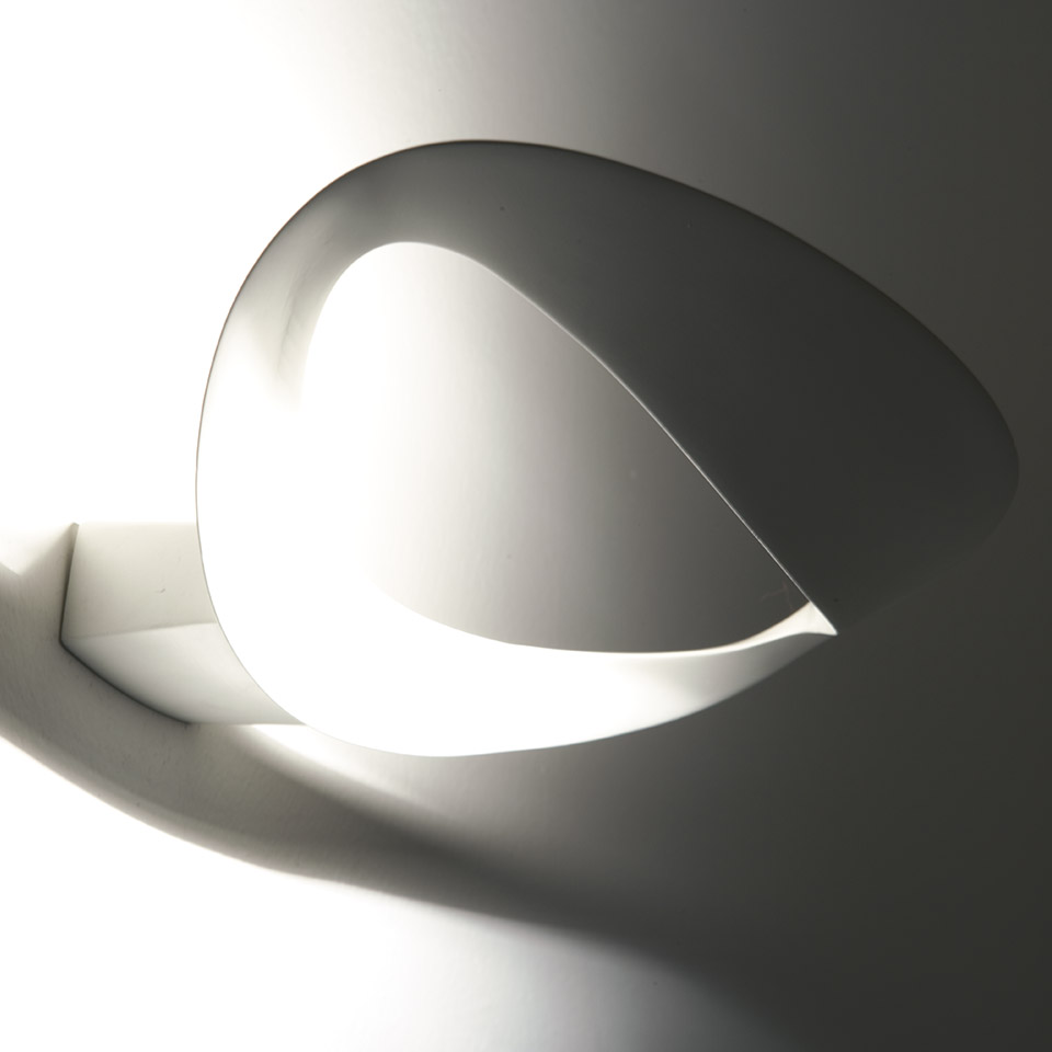 Artemide Mesmeri wall lamp: sculptural white curved shade casting dramatic light and shadow on the wall