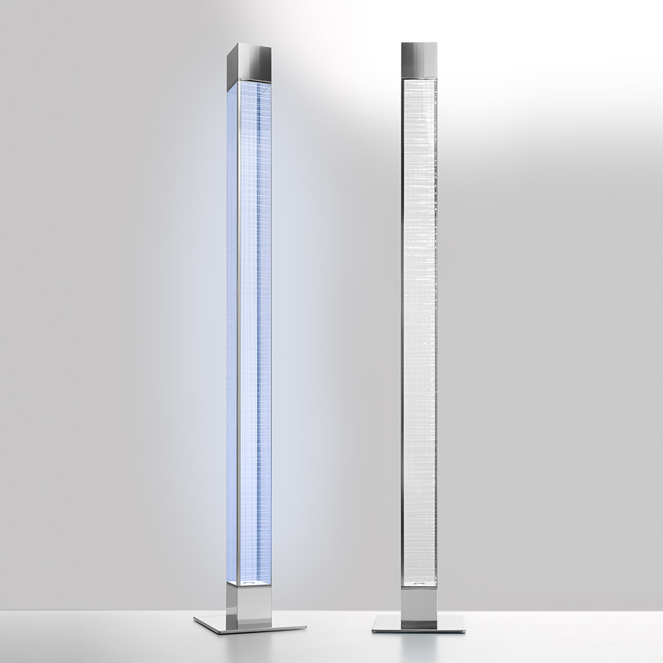 Two Artemide Mimesi floor lamps: left emitting blue-white light, right off, both with slim crystal column body and square chrome base