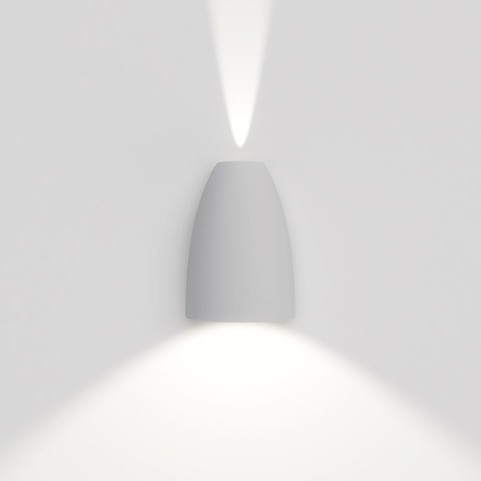 Artemide Molla wall lamp in white, bullet-shaped body emitting upward and downward light beams on a white wall