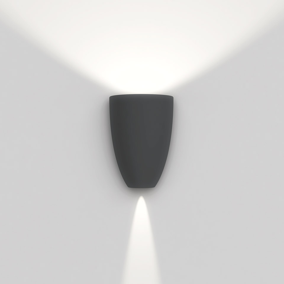 Artemide Molla wall lamp in dark grey, emitting upward wash and downward spot of white light on a white wall