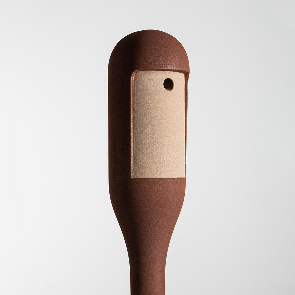 Artemide Needoo lamp head detail: dark brown rounded body with rectangular copper-toned LED light panel and small control button