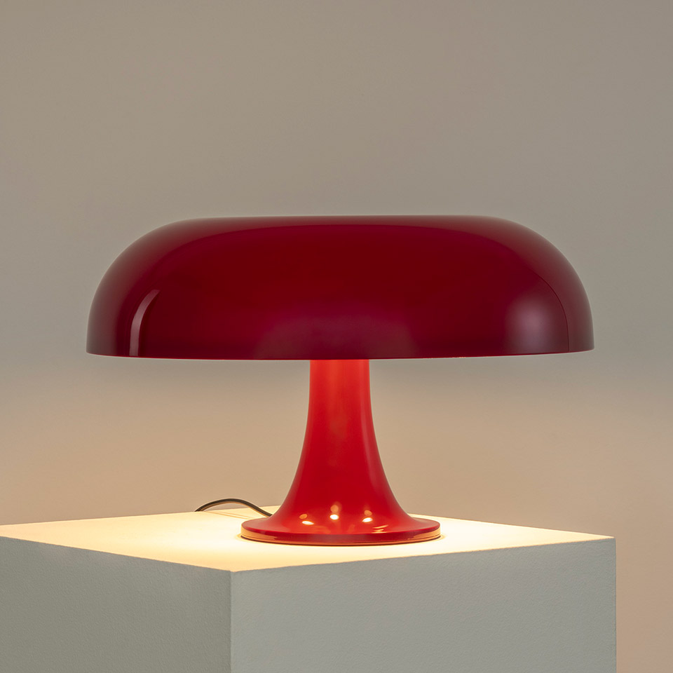 Artemide Nesso table lamp in red, featuring a wide mushroom-shaped shade on a trumpet base, casting warm light downward - 2