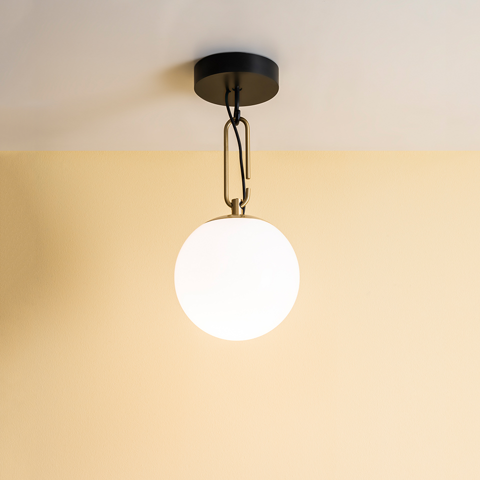Artemide NH ceiling lamp with opal white glass globe shade, brass oval link chain, and matte black ceiling canopy