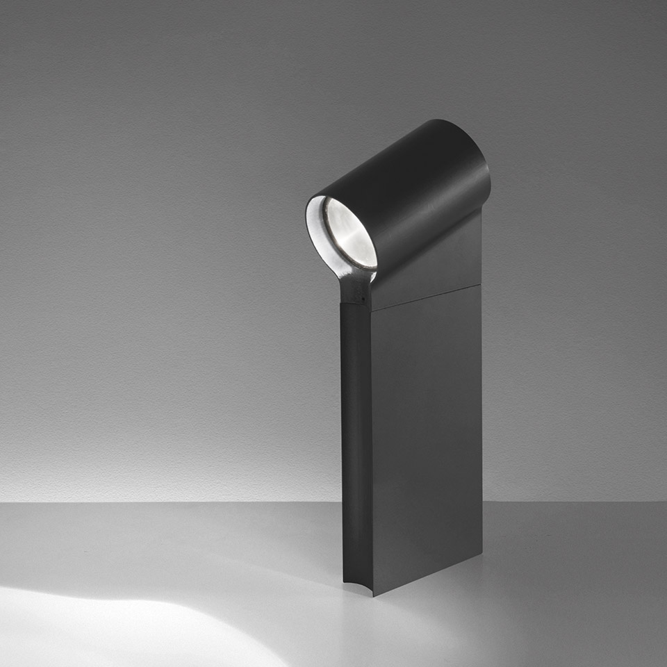 Artemide Oblique outdoor bollard light in dark grey, featuring a pivoting cylindrical LED head casting directional light downward