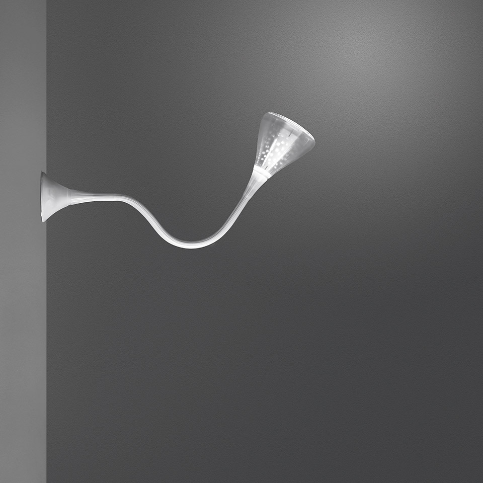 Artemide Pipe wall lamp: sinuous white arm extending from wall, ending in upward-facing conical diffuser emitting soft light