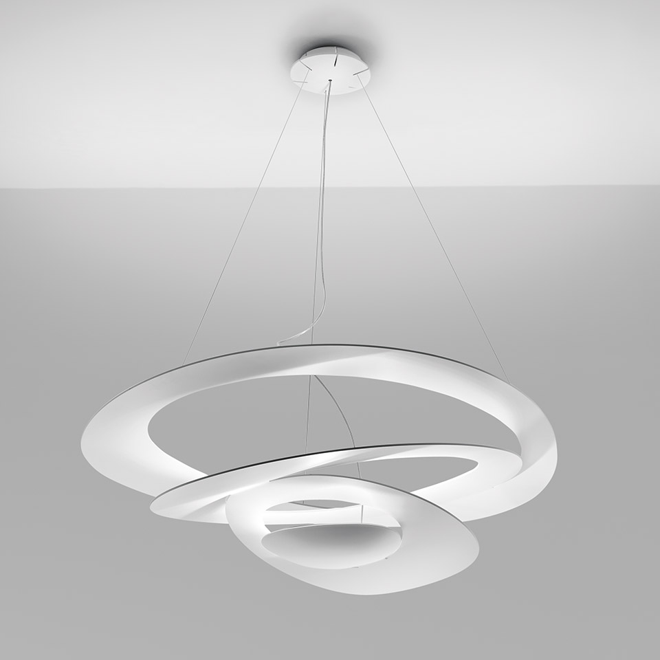 Artemide Pirce pendant lamp in white, featuring a sculptural spiral ribbon form with integrated LED light source, suspended by thin cables.