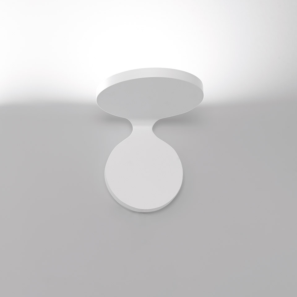 Artemide Rea wall/ceiling lamp in white, featuring two circular discs connected by a curved neck, emitting soft upward light