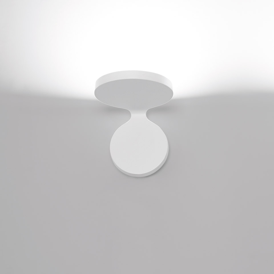 Artemide Rea ceiling spotlight in white, featuring a circular rotating head mounted on a round base, projecting upward light.