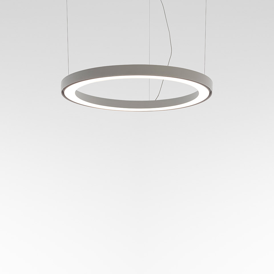 Artemide Ripple pendant lamp: circular ring-shaped LED fixture in grey, emitting soft diffused light along its inner edge, suspended by thin cables
