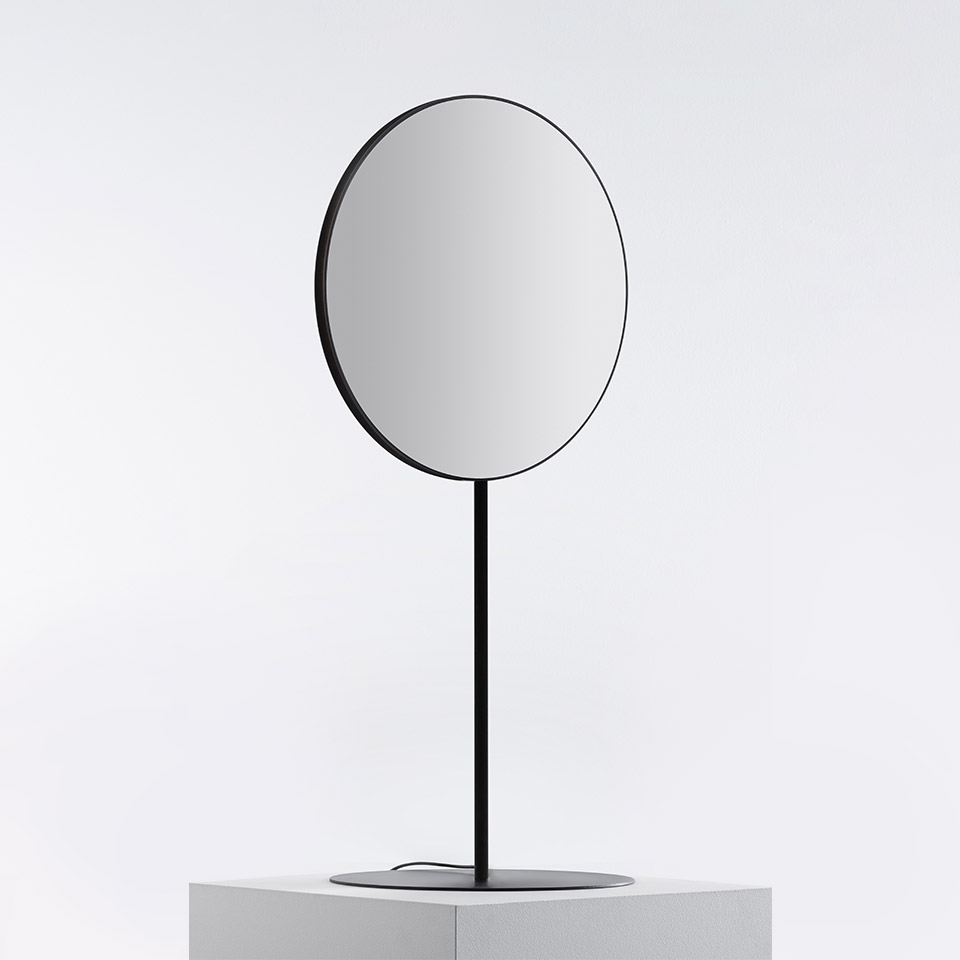 Artemide Se|eS table mirror with circular reflective surface, thin black metal frame, and slender stem on a round base
