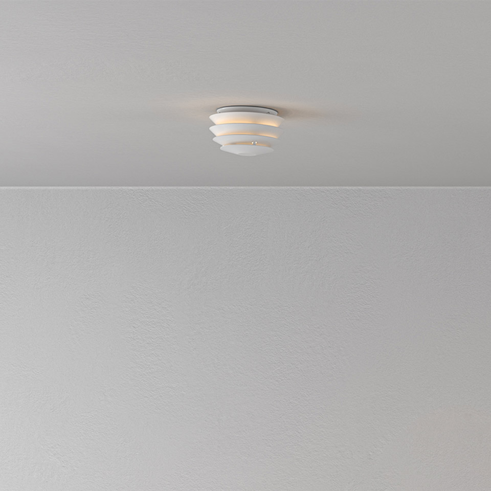 Artemide Slicing ceiling lamp in white, featuring layered horizontal diffuser rings emitting warm light, flush-mounted on a white ceiling