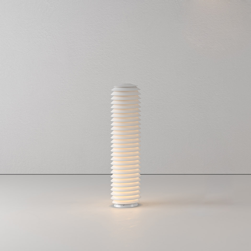 Artemide Slicing floor lamp: tall cylindrical white lamp with stacked horizontal sliced rings emitting warm diffused light