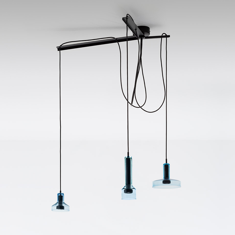 Artemide Stablight: three pendant lights with blue-tinted glass shades hanging at varying heights from a black ceiling bar on black cords