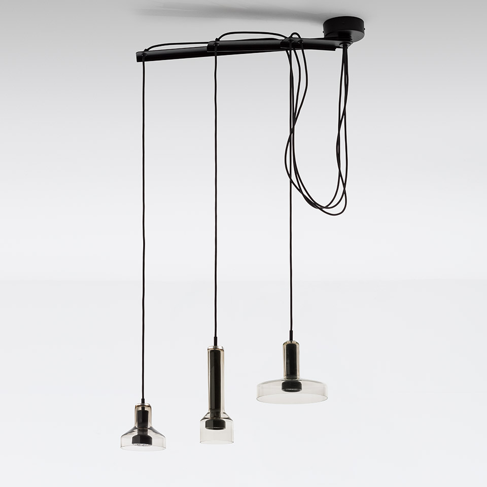 Artemide Stablight: three pendant lights on black rail, varying heights, cylindrical metal bodies with clear glass shades, black cords