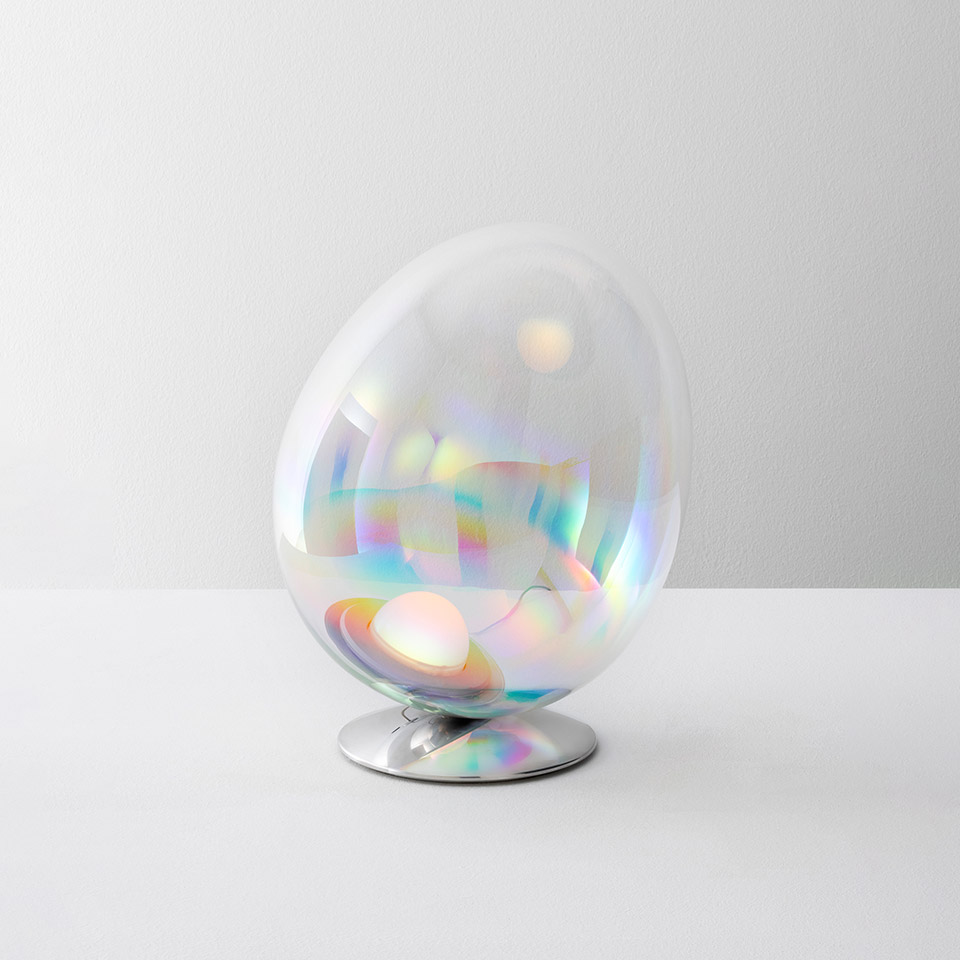 Artemide Stellar Nebula table lamp: egg-shaped iridescent glass diffuser with rainbow reflections on a polished chrome base