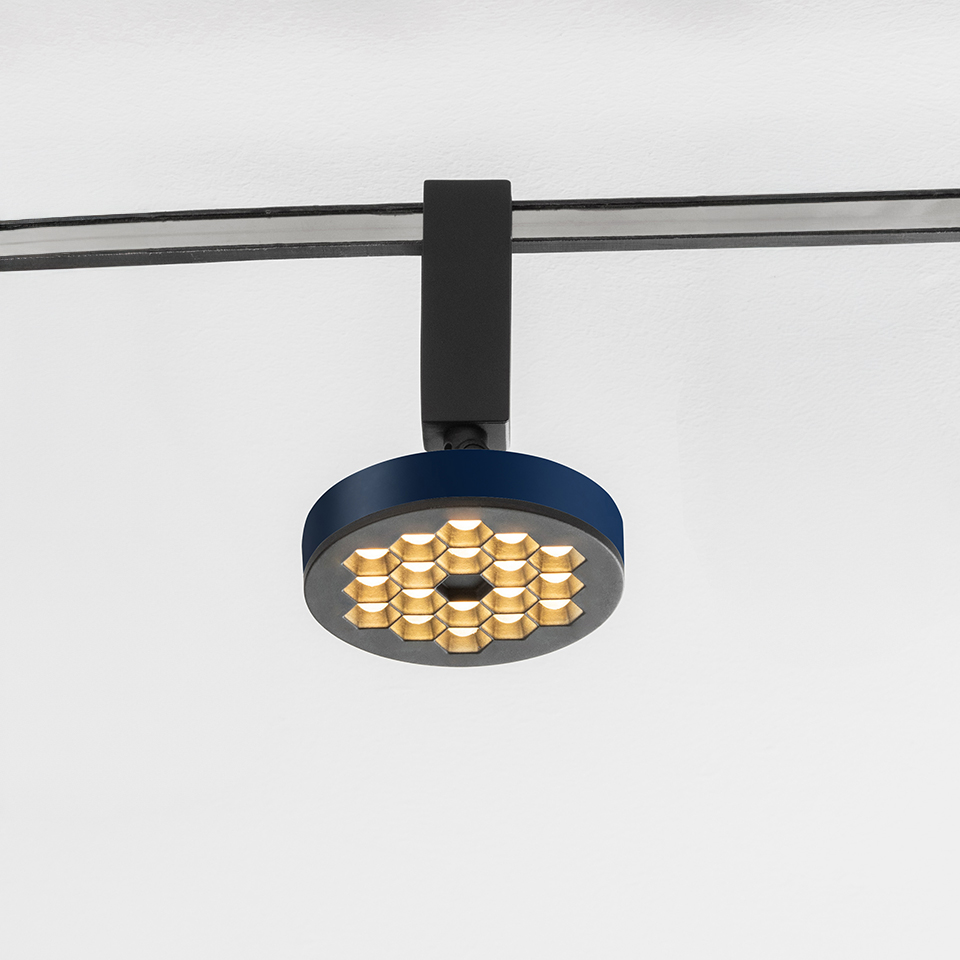 Artemide Sylt track spotlight with circular blue body, honeycomb gold LED array, mounted on black rail system