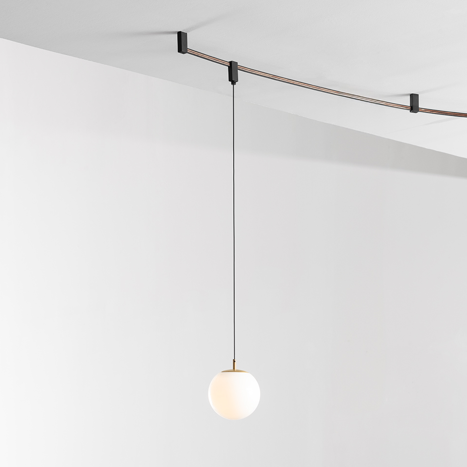 Artemide Sylt pendant lamp: opal white glass sphere hanging from thin black cord on a ceiling-mounted cable track system