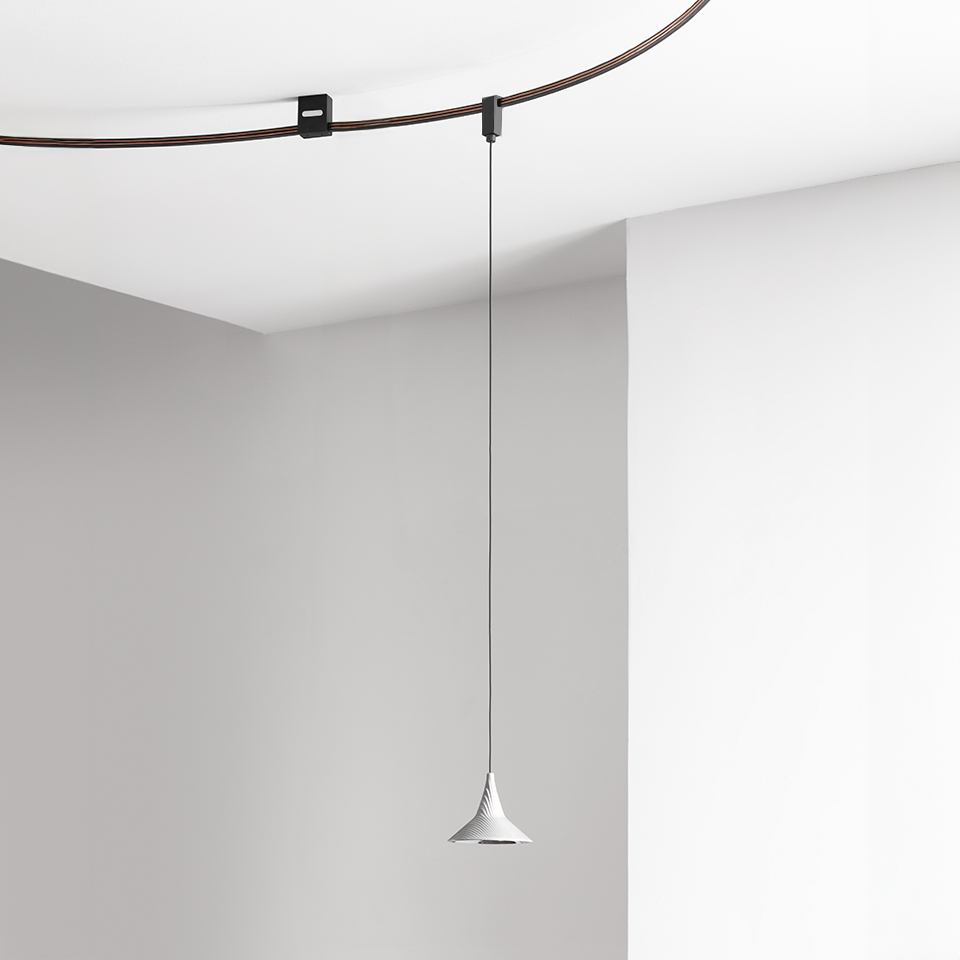 Artemide Sylt pendant lamp with white conical shade hanging from a thin cable on a dark ceiling track system