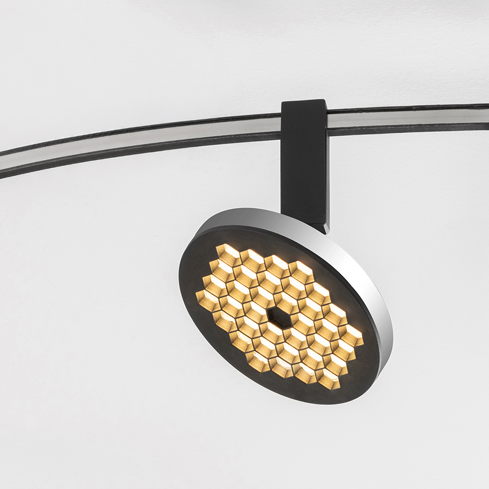 Artemide Sylt track spotlight with circular head featuring honeycomb LED array in gold, mounted on curved black rail