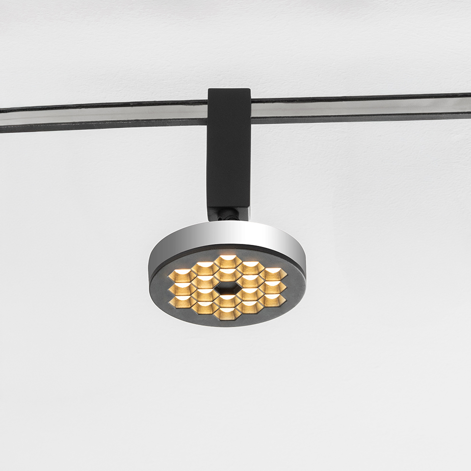 Artemide Sylt track spotlight with circular silver body, honeycomb gold LED array, mounted on black rail system