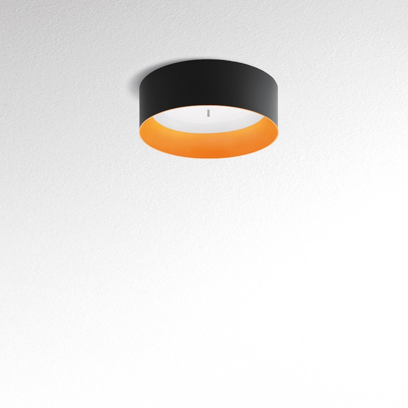 Artemide Tagora Soffitto 570 ceiling lamp: cylindrical black exterior shade with warm orange interior, diffused upward light