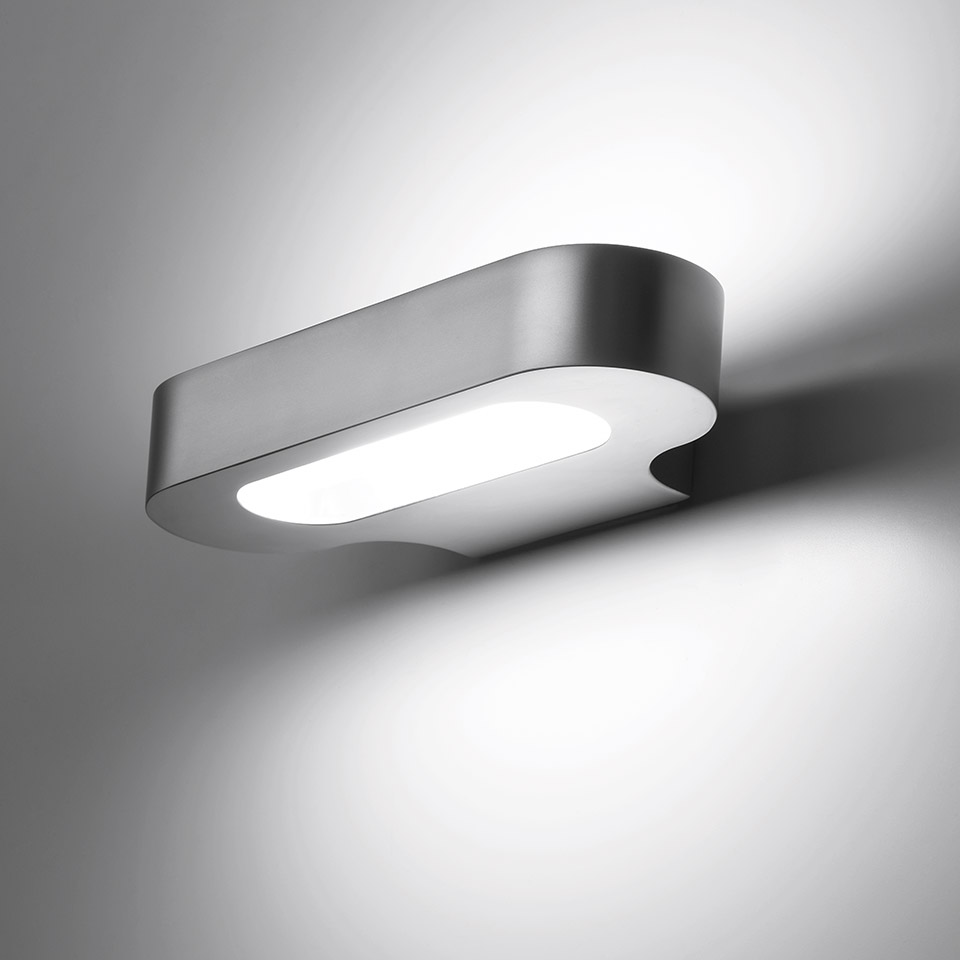 Artemide Talo wall lamp, horizontal oval aluminum body emitting upward and downward white light against a gray wall