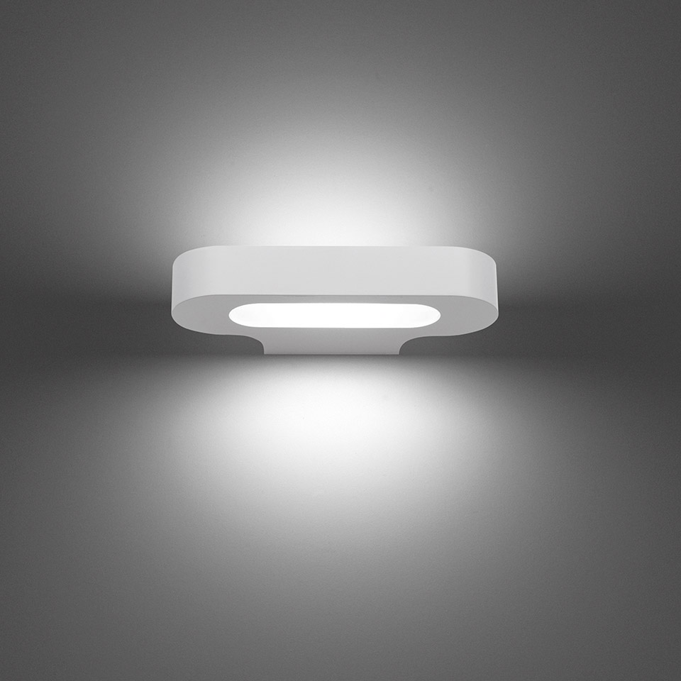 Artemide Talo wall lamp in white, oval shape emitting upward and downward light, creating a soft ambient glow on the wall