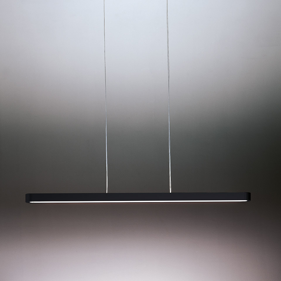 Talo suspension pendant lamp by Artemide: slim dark linear LED bar hanging from two thin cables, emitting warm diffused light.