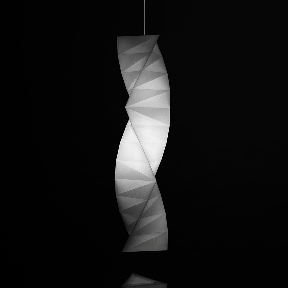 Artemide In-Ei Issey Miyake Tatsuno-Otoshigo pendant lamp: twisted origami-inspired white diffuser emitting soft warm light against dark background
