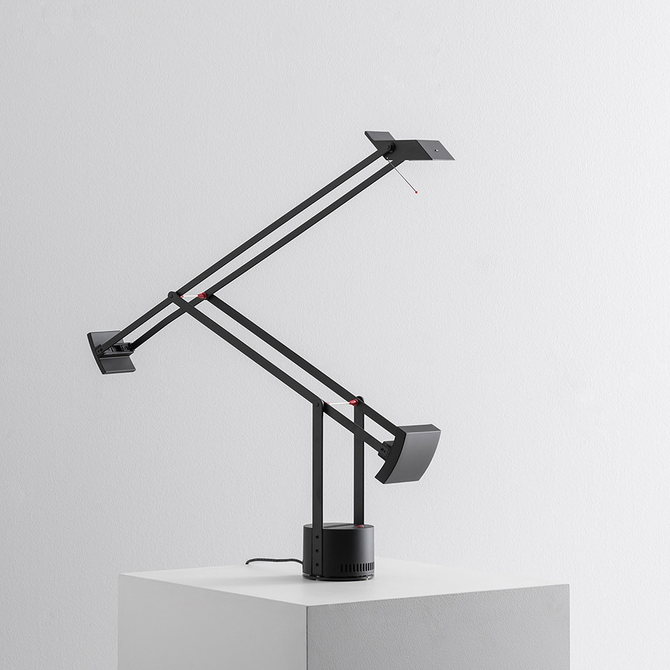 Artemide Tizio black desk lamp with double articulated arms, counterweight balance system, and circular base on white surface