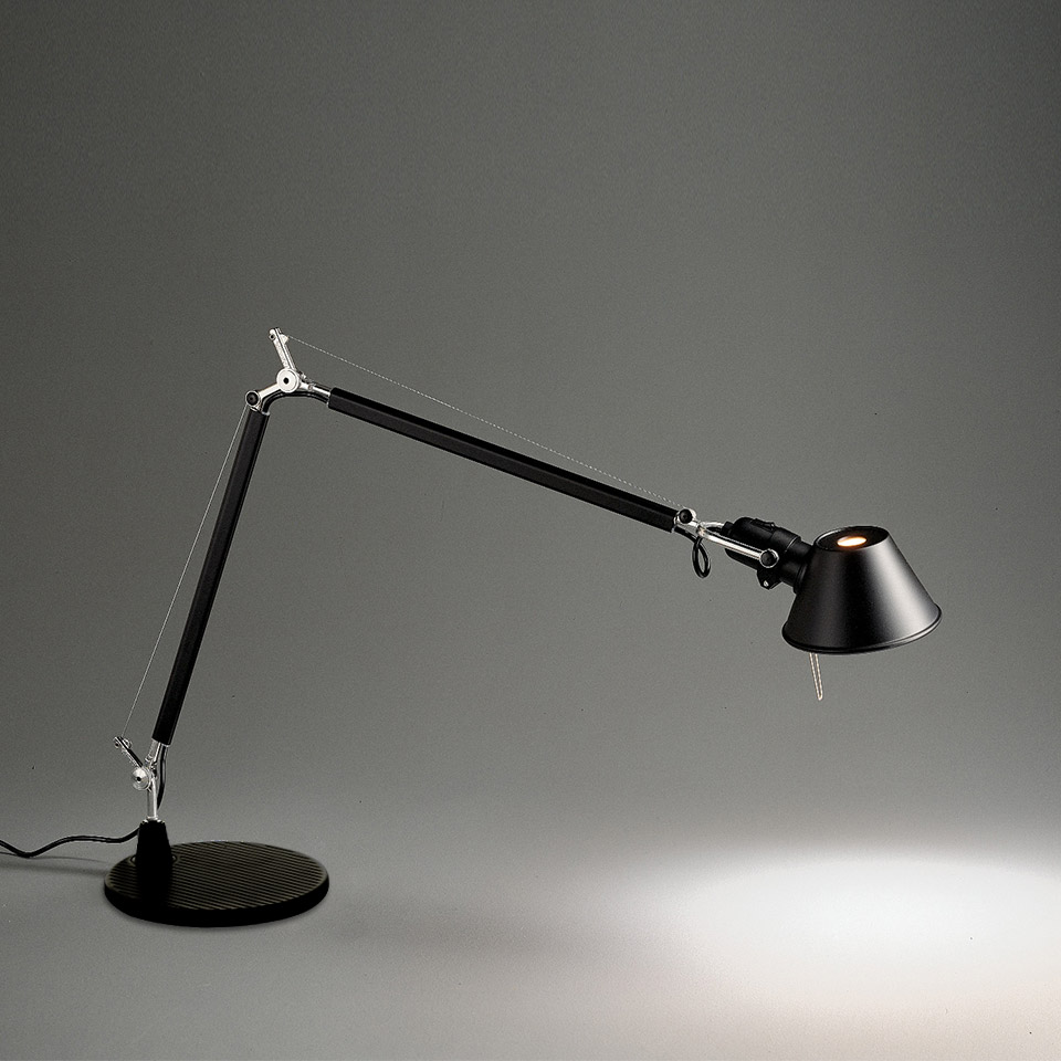 Artemide Tolomeo desk lamp in black, featuring adjustable double-arm with tension cables, conical shade, and round base, illuminating a surface