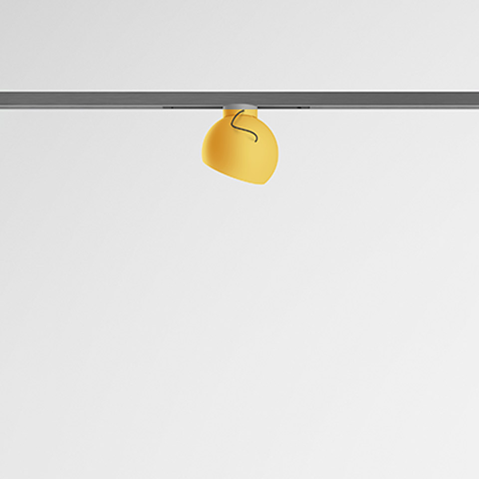 Artemide Turn Around System: yellow rounded spotlight on a gray track rail, with adjustable orientation for directional lighting