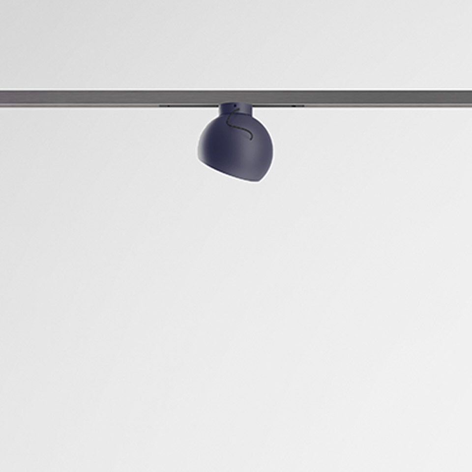 Artemide Turn Around System: dark blue rounded spotlight mounted on a gray ceiling track rail, adjustable directional head