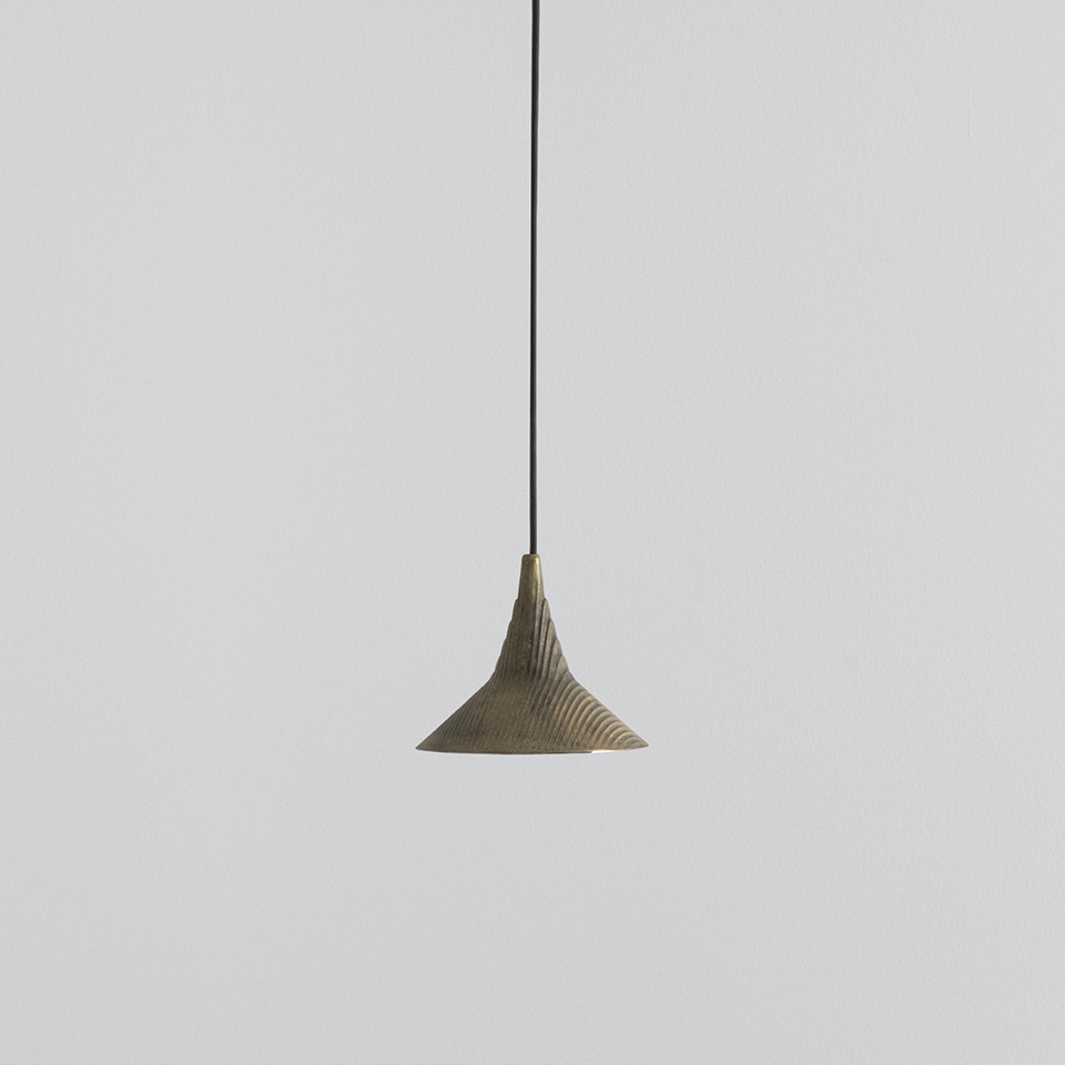 Artemide Turn Around pendant lamp with flared conical bronze-toned shade featuring ribbed texture, suspended from a black cord