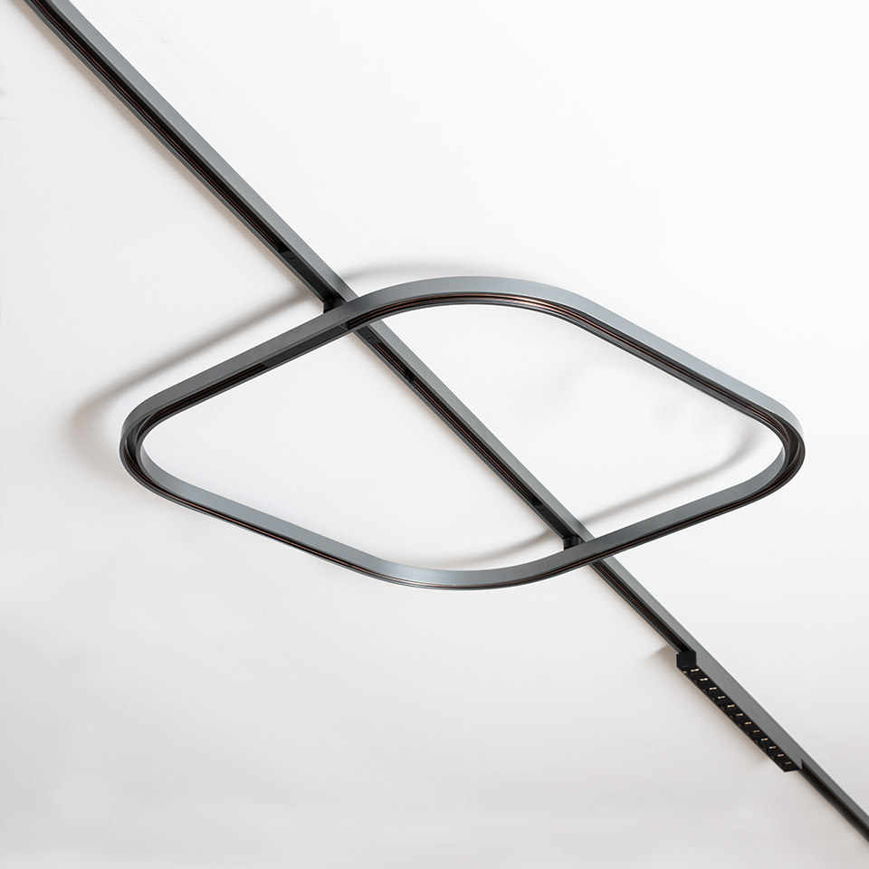 Artemide Turn Around System: dark metal LED ring with eye-shaped curve mounted on ceiling track, minimalist design