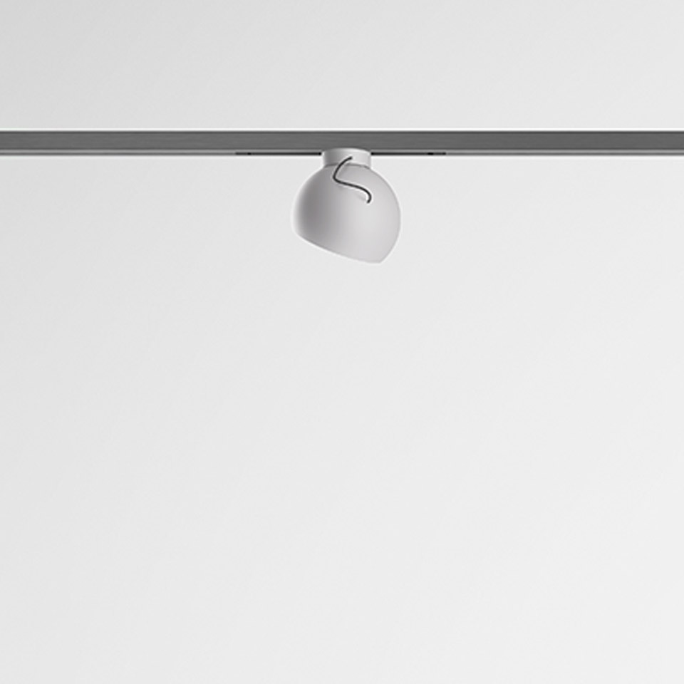 Artemide Turn Around System: white rounded spotlight mounted on a grey ceiling track rail, with adjustable head orientation