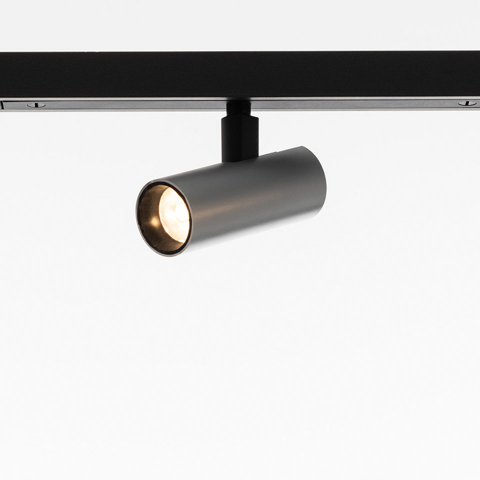 Artemide Turn Around System: dark bronze cylindrical LED track spotlight mounted on black rail, tilted at an angle
